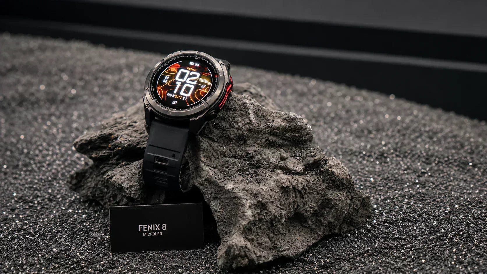  The premium flagship Garmin fenix 8 MicroLED smartwatch resting on a rugged volcanic rock beach, serving as the ultimate adventure layout.