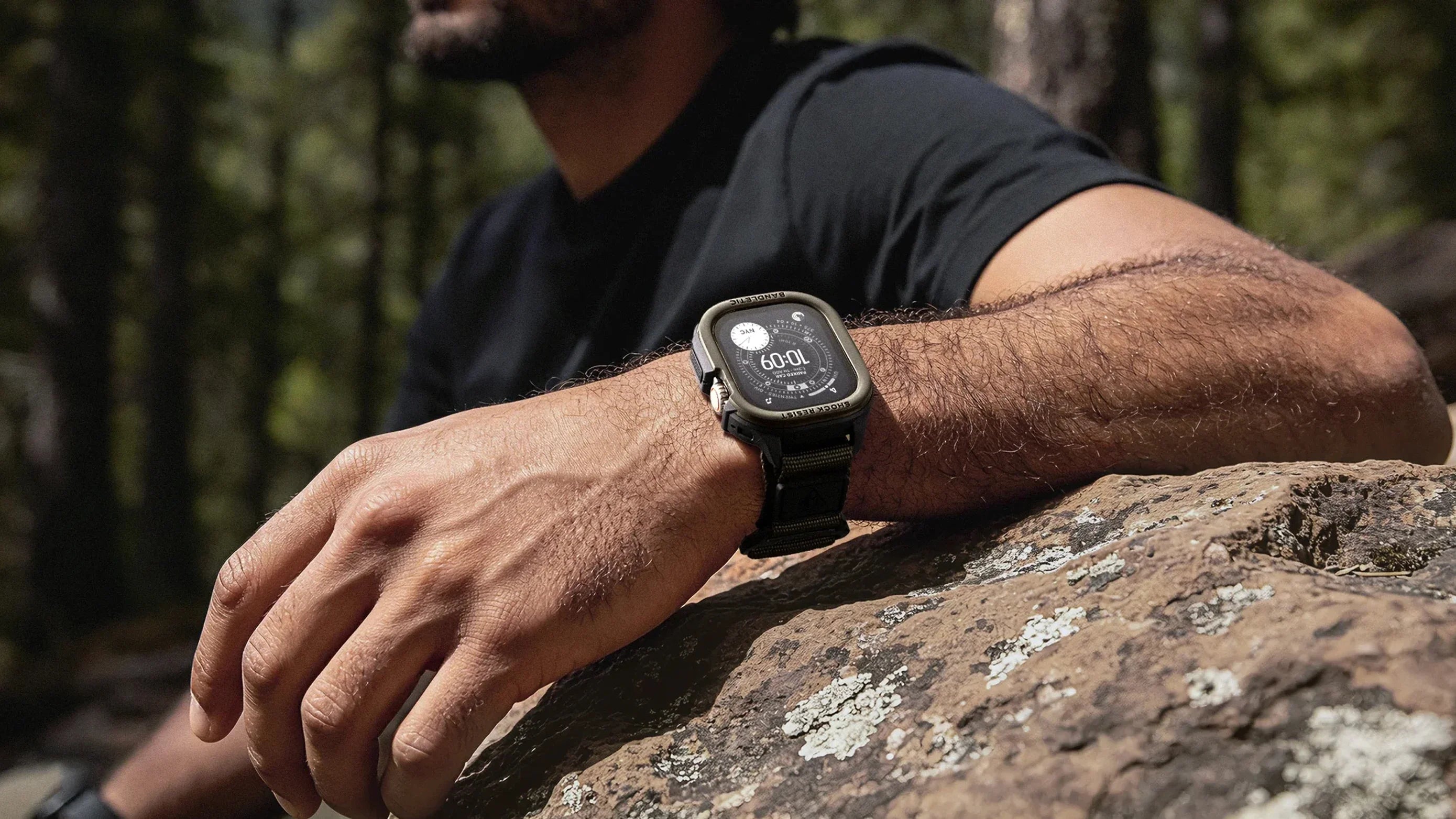 An adventurer wearing the Bandletic Atlas rugged Apple Watch band while resting his arm on a rock on a forest trail.