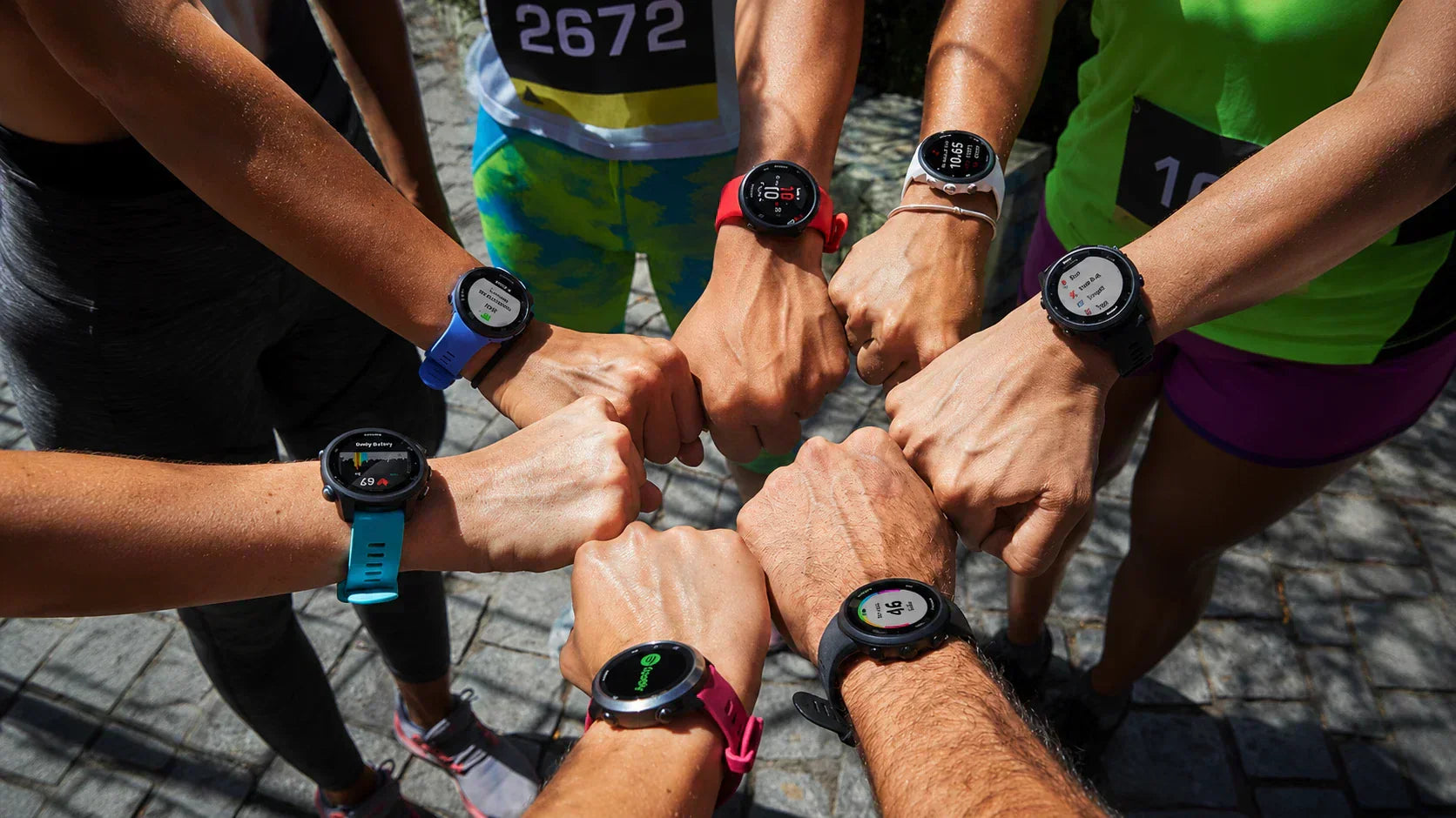 A group of marathon runners aligning their wrists to display various colorful garmin watch bands forerunner models before a race.